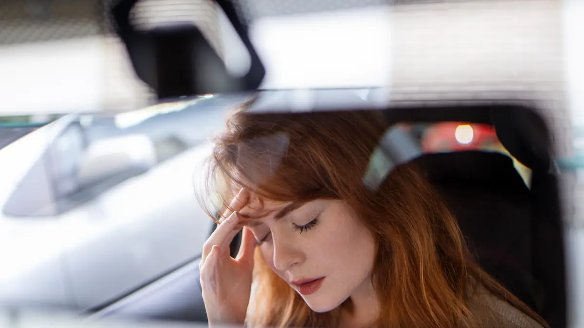 Frau blickt in den Rückspiegel ihres Autos